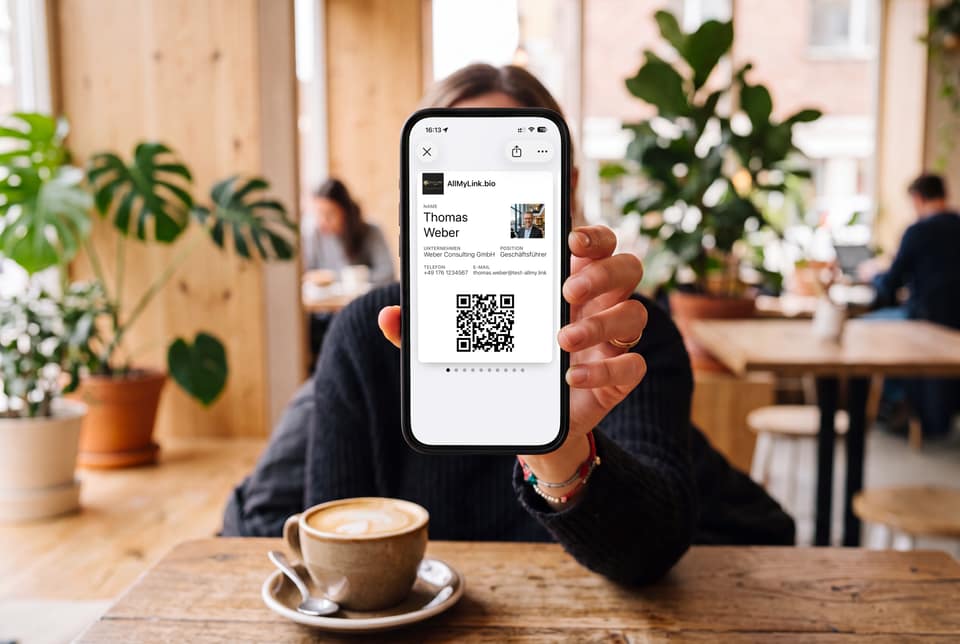 Mit KI gestaltete Szene: Im Café hält eine Kundin ein iPhone mit dem Wallet-Pass von Thomas Weber, fiktive Person, in die Kamera.